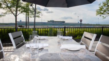 Outdoor table with four seats set up with a view of the Kansas Speedway