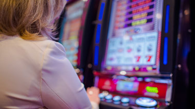 older woman playing slot machine at casino