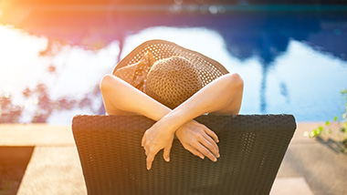 Woman in the summertime, relaxing by the pool in a chair